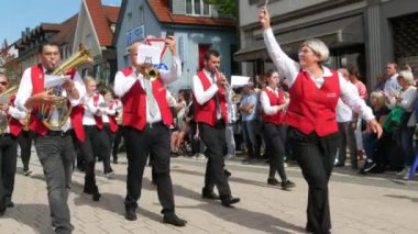 Buhl, Almanya - 11 Eylül 2022: Şehir sokaklarındaki erik hasadının onuruna düzenlenen şenlik geçidi. Kırmızı yelekli güzel giyimli bir orkestra rüzgâr enstrümanları çalıyor ve bir sütun halinde yürüyor..