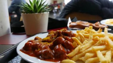 Domates soslu körili sosis ve restoranda patates kızartması. Sağlıksız yağlı gıda konsepti.