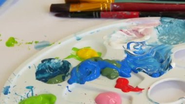 Çizim işlemi. Bir palette çeşitli resimler, bir sanat stüdyosunda bir masanın üzerinde fırçalar..