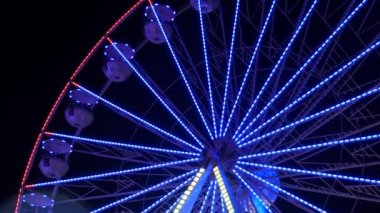 Gece gökyüzünün arka planına karşı büyük renkli bir dönme dolap. Dönme dolap rengarenk bir gece, dışarıdaki rotasyon parkı, yıllık tapınak etkinliği...