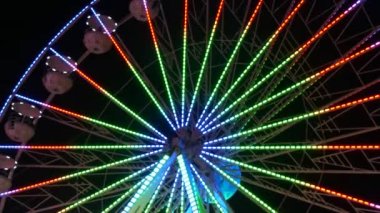 Gece gökyüzünün arka planına karşı büyük renkli bir dönme dolap. Dönme dolap rengarenk bir gece, dışarıdaki rotasyon parkı, yıllık tapınak etkinliği...