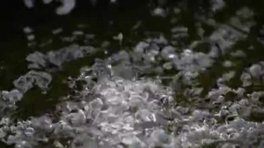 Yavaş hareket eden temiz içme suyu bir su tankına düşer. Damlalar ve sıçramalar yavaşça etrafa yayılır..