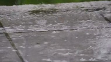 Yağmur damlaları avluya yavaş çekimde düşer. Küresel ısınma kavramı.