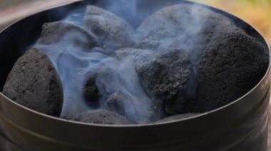 Mangal kömürü bacası piknik yerindeki bir ızgaranın üstüne yerleştirilmiş. Bu metal alet, kömürleri ızgaraya konmadan önce ısıtmak için uygun bir yöntem. Kömür yanıyor..