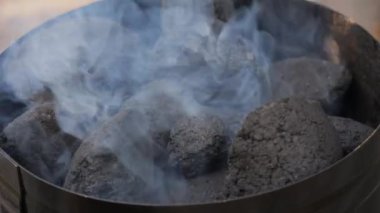 Mangal kömürü bacası piknik yerindeki bir ızgaranın üstüne yerleştirilmiş. Bu metal alet, kömürleri ızgaraya konmadan önce ısıtmak için uygun bir yöntem. Kömür yanıyor..