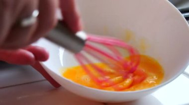 Bir kadın özel bir silikon çırpıcıyla yumurtayı kırbaçlıyor. Yavaş çekimde ev yapımı çörekler yapıyor..