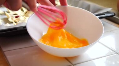 Bir kadın özel bir silikon çırpıcıyla yumurtayı kırbaçlıyor. Yavaş çekimde ev yapımı çörekler yapıyor..