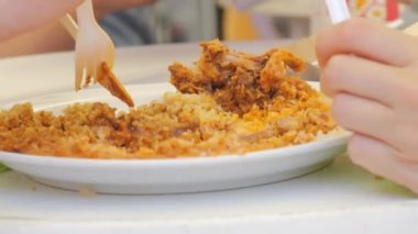 İnsanlar bir markette, eko ahşap çatal ve bıçaklarla tabaktan pirinç ve et yiyorlar..