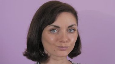 Düşünceli bir şekilde kameraya bakan güzel bir genç kadının portresi. Mor yavaş çekim arka planında bir kadının durağan duyguları.