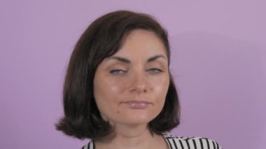 Düşünceli bir şekilde kameraya bakan güzel bir genç kadının portresi. Mor yavaş çekim arka planında bir kadının durağan duyguları.