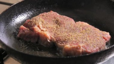 Baharatlı, tereyağlı ve sarımsaklı biftek yavaş çekimde tavada kızarır..