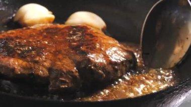 Baharatlı, tereyağlı ve sarımsaklı biftek yavaş çekimde tavada kızarır..