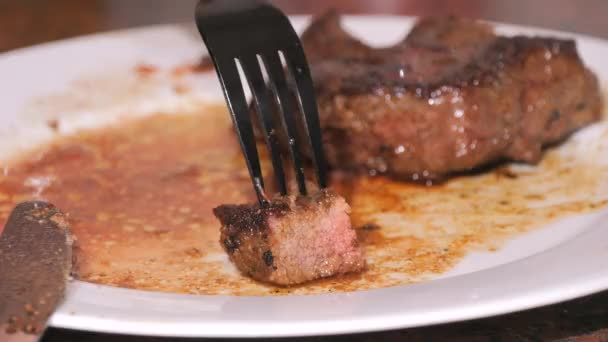大块刚烤好的牛肉牛排放在盘子里 慢动作的中等程度烤肉 一把刀叉把一块近视的东西切下来 — 图库视频影像