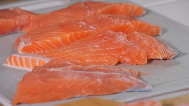 新鮮な赤い魚の断片は ゆっくりとした動きで塩で振られています サーモンステーキの味付け 焼く前に生ステーキにスパイスを加えるシェフ — ストック動画