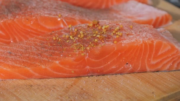 新鮮な赤い魚の断片は スパイスと塩でスパイスで振られ スローモーションが近づいています サーモンステーキの味付け 焼く前に生ステーキにスパイスを加えるシェフ — ストック動画