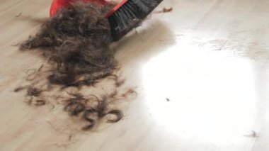 Yerde bir sürü saç var. Süpürge saçı bir kepçe içine süpürür.