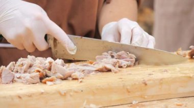 Aşçının elleri domuz etini küçük parçalara ayırır ve büyük bir bıçakla yakından bakar..