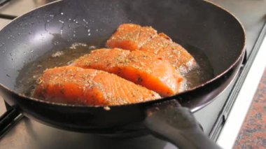 Baharatlı taze kırmızı balık filetosu. Somon fileto eti bir tavada ayçiçeği yağında kızartılır, yakın çekim, yavaş çekim..