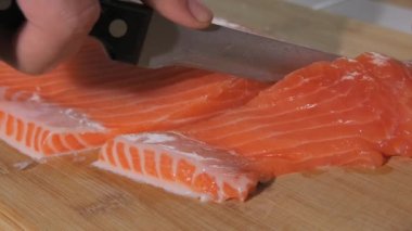 Şef bir bıçak ile taze kırmızı balık filetosu keser. Biftek için çiğ somon pişiriyorum. Yakın çekim..