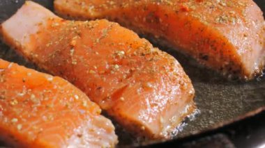 Baharatlı taze kırmızı balık filetosu. Somon fileto eti bir tavada ayçiçeği yağında kızartılır, yakın çekim, yavaş çekim..