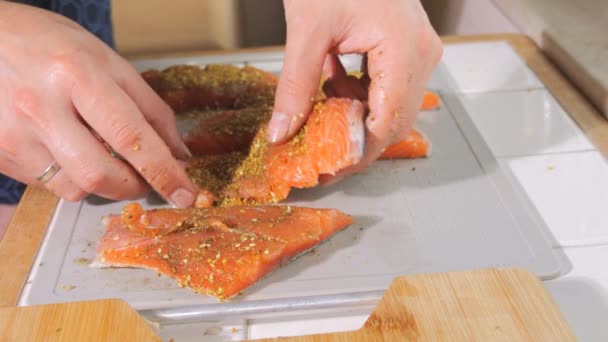 新鮮な赤い魚の断片は スパイスと塩でスパイスで振られ スローモーションが近づいています サーモンステーキの味付け シェフはベーキングする前に手でステーキをこすります — ストック動画