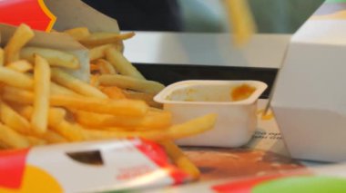 Bir adam patates kızartmasını fast food restoranında sosa batırır. Çöp, yağlı yiyecekler..