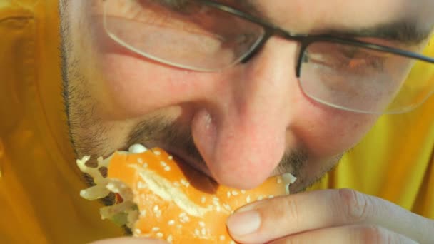 Ein Junger Mann Gelben Shirt Isst Mit Appetit Einen Hamburger — Stockvideo