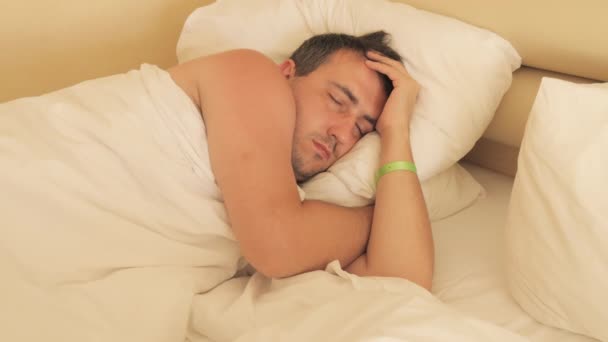 Jovem Dorme Quarto Hotel Uma Cama Branca Travesseiros Uma Pulseira — Vídeo de Stock