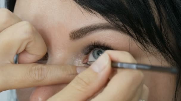一位漂亮的年轻女子在一家美容室里用一把特殊的刷子做眼妆 她是一位专业的化妆师 她正在做时尚的晚妆 — 图库视频影像