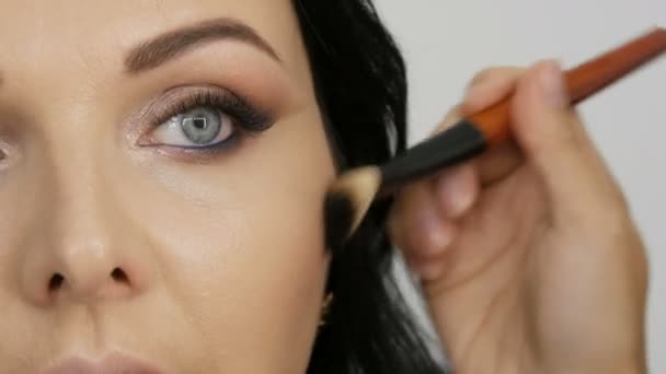 在准备晚妆时 专业的造型师用一种特殊的刷子在一位年轻漂亮的女模特的脸上涂上腮红 — 图库视频影像