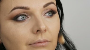 Akşam makyajı hazırlığı, profesyonel makyaj sanatçısı genç ve güzel bir kadın modelin yüzüne özel bir fırçayla allık sürüyor..