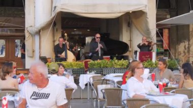 Venedik, İtalya - 5 Eylül 2023: Dinlenen turistlerin masalarda oturduğu, müzisyenlerin müzik enstrümanları çaldığı rahat bir restoran.