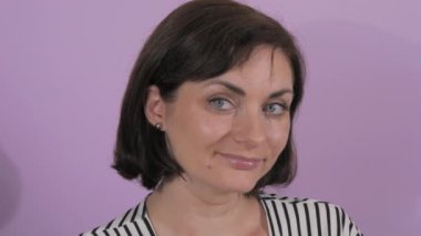 Düşünceli bir şekilde kameraya bakan güzel bir genç kadının portresi. Mor yavaş çekim arka planında bir kadının durağan duyguları.