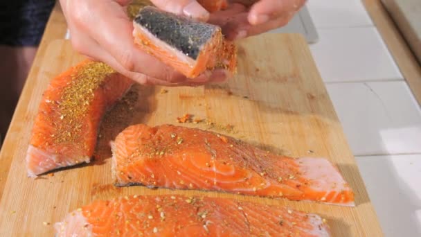 一片鲜红的鱼在慢镜头下撒满了香料和盐 调味鲑鱼牛排 厨师在烤牛排之前用手揉搓它 — 图库视频影像