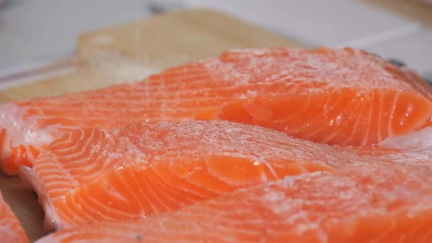 一片鲜红的鱼被盐撒在慢动作的近视中 调味鲑鱼牛排 厨师烘烤前在生牛排上加调味料 — 图库视频影像