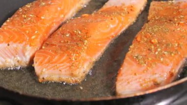 Baharatlı taze kırmızı balık filetosu. Somon fileto eti bir tavada ayçiçeği yağında kızartılır, yakın çekim, yavaş çekim..