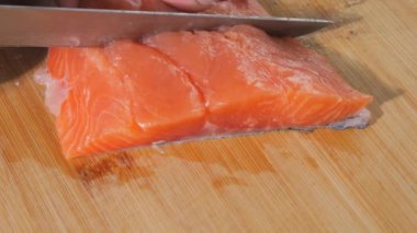 Şef bir bıçak ile taze kırmızı balık filetosu keser. Biftek için çiğ somon pişiriyorum. Yakın çekim..