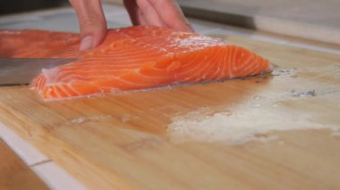 Şef bir bıçak ile taze kırmızı balık filetosu keser. Biftek için çiğ somon pişiriyorum. Yakın çekim..
