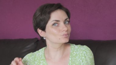 Yeşil gözlü ve kısa saçlı güzel bir kadın dans ediyor, eğleniyor ve gülümsüyor..