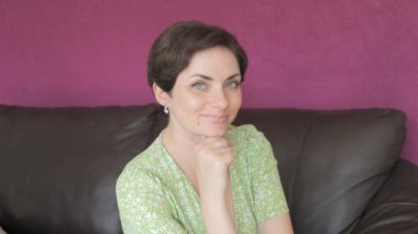 Yeşil gözlü ve kısa saçlı güzel bir kadın. Düşünceli bir şekilde kameraya bakıyor ve gizemli bir şekilde yavaş çekimde gülümsüyor..