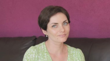 Yeşil gözlü ve kısa saçlı güzel bir kadın dans ediyor, eğleniyor ve gülümsüyor..