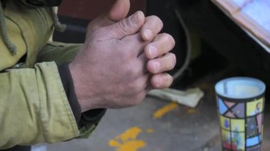Zavallı evsiz bir adam kışın sokakta dizlerinin üzerine çöküp sadaka dilenir ve elleri bir dilenme jesti ile bağlanır. Kalabalık yavaş çekimde geçip gidiyor..