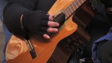 Yavaş çekimde gitar çalan bir sokak müzisyeninin elleri.