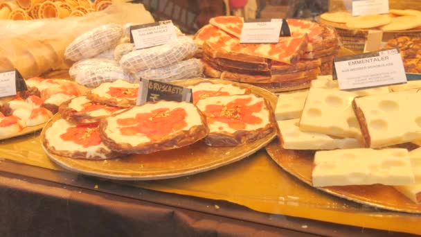 チーズの形をした様々なチョコレート製品 ピザやブロシェッタのスライス クリスマスマーケットのカウンターにはさまざまなチョコレートがあります ドイツ語でチョコレートの名前のサイン スイーツコンセプト — ストック動画
