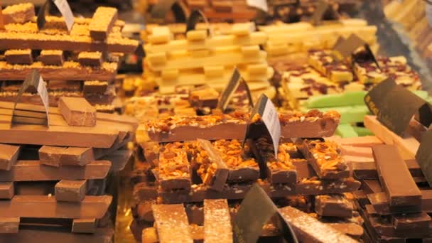夜のクリスマスマーケットのカウンターには さまざまなチョコレートがあります ドイツ語でチョコレートの名前のサイン スイーツコンセプト — ストック動画