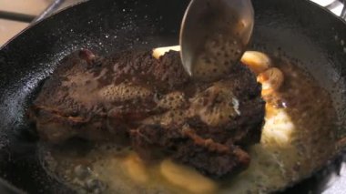 Baharatlı, tereyağlı ve sarımsaklı biftek yavaş çekimde tavada kızarır..