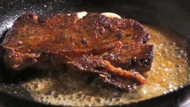 Baharatlı, tereyağlı ve sarımsaklı biftek yavaş çekimde tavada kızarır..