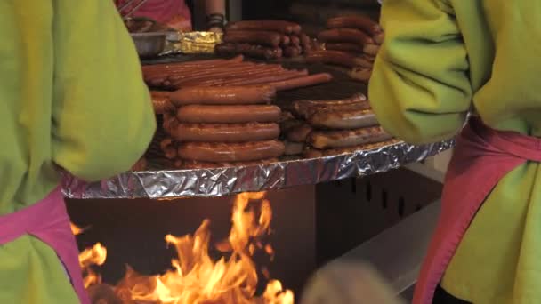 ソーセージを揚げて販売する大きな丸い吊りグリル スローモーションで食品市場での火災ロースト肉製品の大きな炎 — ストック動画