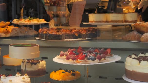 店のカウンターにはさまざまな美味しい新鮮なケーキ 窓ガラスに映し出される人々 — ストック動画