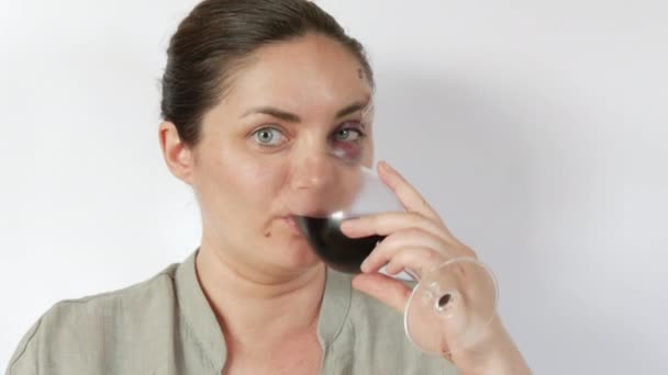 一个女人在一个年轻女人的眼皮底下 喝着杯子里的葡萄酒 杯子里有一个大的 真正的青肿的血肿 额头上有新鲜的紫色青肿和划伤 家庭暴力受害者惊惶的脸 — 图库视频影像